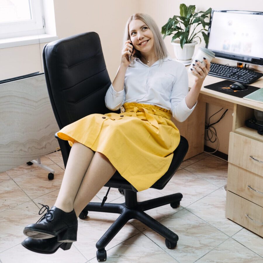 SMM specialist, Social Media Expert, Remote Social Media Pro. Young girl SMM manager with a phone at the workplace near computer with open social media page website.